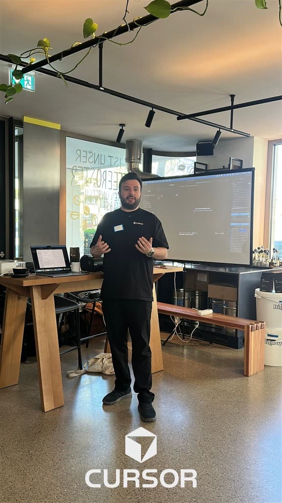Eyad giving a presentation at Café Cursor with a code editor on the main screen
